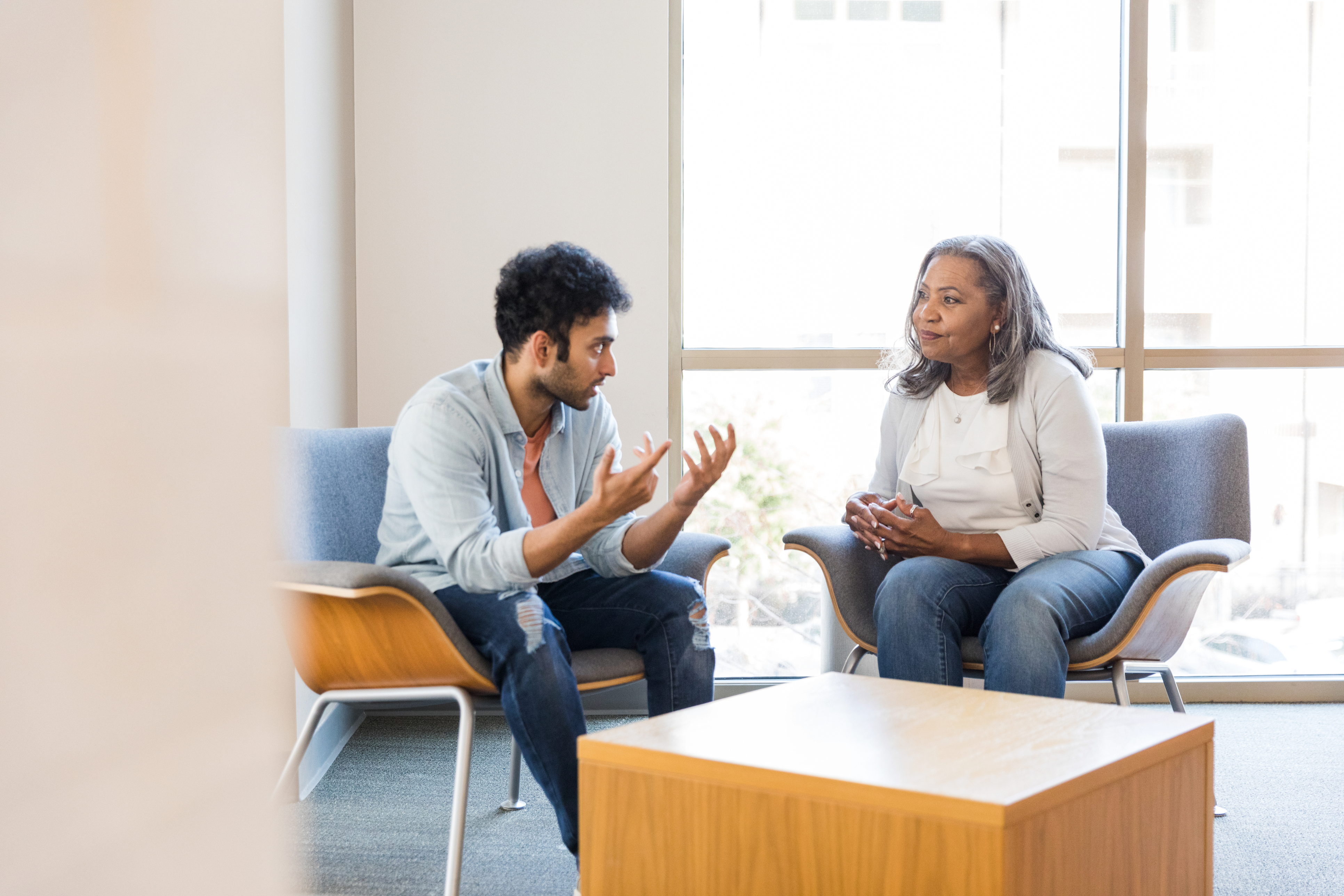 Young man gestures while sharing with female counselor Young man gestures while sharing with female counselor